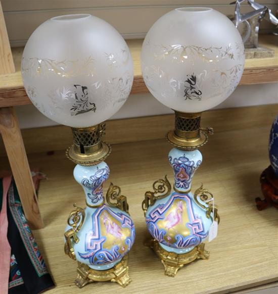 A pair of Napoleon III Paris porcelain ormulu mounted oil lamps, complete with clear glass etched shades, 63cm total height